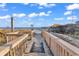Beach access via a wooden boardwalk through dunes under a partly cloudy blue sky at 6000 N North Ocean Blvd. # 329, North Myrtle Beach, SC 29582