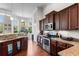 A modern kitchen features granite countertops, wooden cabinetry, stainless steel appliances, and abundant natural light at 9060 Abingdon Dr., Myrtle Beach, SC 29579