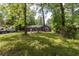 Large backyard surrounded by mature trees, featuring a trampoline and a trailer at 106 Azalea Dr., Conway, SC 29526