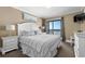 Comfortable main bedroom with ocean view balcony, white furniture, and soft, stylish decor at 108 N Ocean Blvd. # 301, North Myrtle Beach, SC 29582