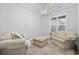 Cozy living room with neutral armchairs, an upholstered ottoman, a modern light fixture, and a window at 1196 Fiddlehead Way, Myrtle Beach, SC 29579
