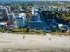 Aerial view of oceanfront complex with pristine beach, multiple buildings, and lush landscaping in a vibrant city setting at 201 77Th Ave. N # 828, Myrtle Beach, SC 29572