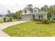 Beautiful single Gathering home with a stone and white exterior, complimented by a green lawn and palm trees at 2928 Moss Bridge Ln., Myrtle Beach, SC 29579