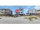 Desirable beach house with red metal roof on stilts with a wooden walkway on a sandy lot at 324 S Waccamaw Dr., Garden City Beach, SC 29576