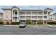 Three-story condo building with white balconies and a parking lot in front at 3979 Forsythia Ct. # 203, Myrtle Beach, SC 29588