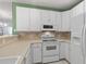 Close-up of the well-lit kitchen with white cabinets and appliances including a built-in microwave at 432 Warrington Way # 432, Murrells Inlet, SC 29576