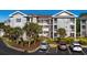 Three-story condo building features brick facade, white trim, balconies, and palm tree landscaping with parking at 4749 Wild Iris Dr. # 205, Myrtle Beach, SC 29577