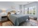 Sunlit bedroom with large window, a plush quilted bed, and decorative lamps and rug for added warmth and style at 4803 Bovardia Pl. # 104, Myrtle Beach, SC 29577
