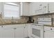 Bright kitchen featuring white cabinets, granite countertops, tiled backsplash, and modern appliances at 4803 Bovardia Pl. # 104, Myrtle Beach, SC 29577