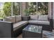 This screened porch boasts a glass table, modern outdoor furniture, neutral cushions and serene backyard views at 4803 Bovardia Pl. # 104, Myrtle Beach, SC 29577