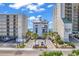 View of condos and hotel between other buildings with brick-paved parking, palm trees, and blue skies at 4814 Greenhaven Dr., North Myrtle Beach, SC 29582