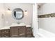 Updated bathroom boasts a decorative round mirror, vanity with drawers, and tiled shower at 668 S Waccamaw Dr., Murrells Inlet, SC 29576