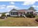 Spacious backyard with a well-maintained lawn, red shuttered house, and inviting patio area at 761 Drawbridge Dr., Conway, SC 29526