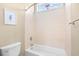 Tiled bathroom with a toilet, shower-tub combination, a towel bar, and a window with a flower accent at 8050 Wacobee Dr., Myrtle Beach, SC 29579