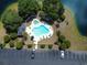 Aerial view of a community pool with a hot tub, lounge chairs, and umbrella-covered tables at 1041 True Blue Dr. # 37A, Pawleys Island, SC 29585
