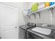 Modern laundry room featuring gray washer and dryer, storage shelving, and white door at 1048 Longwood Bluffs Circle, Murrells Inlet, SC 29576