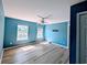 The bedroom features cool blue walls, a ceiling fan, two windows, and light-wood floors at 119 Brentwood Dr. # D, Murrells Inlet, SC 29576