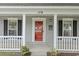 Close-up of the front porch, showcasing the bright red door, white pillars, and detailed trim at 119 Pickerel Blvd., Longs, SC 29568