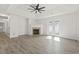 Open living room with a fireplace, hardwood floors, a tray ceiling with ceiling fan, and bright lighting at 119 Pickerel Blvd., Longs, SC 29568