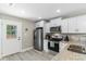 Well-lit kitchen with stainless steel refrigerator, white cabinets and granite countertops at 1396 Highway 129, Galivants Ferry, SC 29544