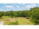 Picturesque landscape featuring a storage shed, lush greenery, and mature trees under a partly cloudy sky at 151 Saddle Dr., Loris, SC 29569