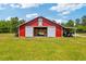 Large red barn with sliding doors and covered parking, ideal for agricultural or storage purposes at 151 Saddle Dr., Loris, SC 29569