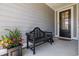 Cozy porch with black bench, decorative plants, and a black front door with glass panel at 179 Hyacinth Loop, Murrells Inlet, SC 29576