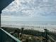 A beautiful ocean view with umbrellas on the beach, palm trees, and picnic tables below from a condo balcony at 201 N Ocean Blvd. # 2536, Myrtle Beach, SC 29572