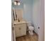 Cozy powder room with light blue paint, a cream vanity with a sink and a toilet, and light wood-look floors at 214 Carolina Dr., Loris, SC 29569