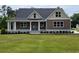 Charming home featuring an inviting front porch and lush green lawn with manicured landscaping at 214 Carolina Dr., Loris, SC 29569