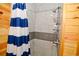 This tiled shower features a blue and white striped shower curtain, shower caddy, and mounted shower head at 219 27Th Ave. N, North Myrtle Beach, SC 29582