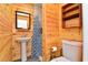 Bathroom featuring knotty pine, a pedestal sink, toilet, wood shelving, and a shower behind a patterned curtain at 219 27Th Ave. N, North Myrtle Beach, SC 29582