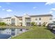A condo exterior featuring a pond, beige siding, screened-in porches, and neatly kept lawns and shrubs at 2258 Essex Dr. # G, Surfside Beach, SC 29575