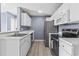 A well-organized kitchen featuring white cabinets, stainless steel appliances, gray wood floors, and light blue walls at 2258 Essex Dr. # G, Surfside Beach, SC 29575