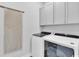 Modern laundry room with sleek cabinetry, macrame wall art, and front-load washer and dryer at 2525 Watershed Way, Longs, SC 29568