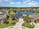 Aerial view of a brick home, lush landscaping, and a serene lake with fountain at 2940 Tigers Eye Rd., Little River, SC 29566