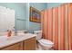 Colorful bathroom with a striped shower curtain, light wood vanity, and a lively Margarita-themed painting at 311 2Nd Ave. N # 210, North Myrtle Beach, SC 29582