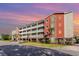 Low-angle view of a multi-story condo building with multiple balconies and vibrant landscaping at 311 2Nd Ave. N # 210, North Myrtle Beach, SC 29582