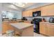 Open kitchen with island, black appliances and light wood cabinetry at 311 2Nd Ave. N # 210, North Myrtle Beach, SC 29582
