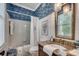 Charming bathroom features patterned wallpaper, white tile, a shower-tub combination, and a granite vanity at 402 E Broad St., Hemingway, SC 29554