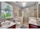 Elegant bathroom with glass shower, double vanities, neutral tile, and large window with lush views at 402 E Broad St., Hemingway, SC 29554