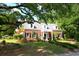 Charming brick home features a manicured front lawn and inviting entrance with white columns and a balcony above at 402 E Broad St., Hemingway, SC 29554