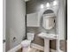 Modern powder room with a stylish pedestal sink, toilet, and elegant mirror, creating a sophisticated ambiance at 531 Oak Landing Dr., Myrtle Beach, SC 29588