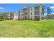 Exterior view of a multi-story condo building, green lawn, and screened porches at 545 White River Dr. # 15 D, Myrtle Beach, SC 29579
