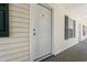 Exterior view of a white condo door with dark green shutters on windows and gray tile flooring at 545 White River Dr. # 15 D, Myrtle Beach, SC 29579