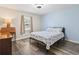 Comfortable bedroom with a light blue accent wall, wood-look floors, and a window offering a pleasant view at 605 62Nd Ave. N, Myrtle Beach, SC 29572
