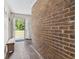 Hallway with a brick wall, wood-look flooring, and an open doorway leading to a bright outdoor view at 605 62Nd Ave. N, Myrtle Beach, SC 29572