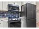 Well-equipped kitchen with modern black appliances, white cabinetry, and contrasting blue backsplash at 605 62Nd Ave. N, Myrtle Beach, SC 29572
