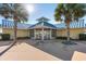 View of the community clubhouse, with glass doors and surrounded by landscaped grounds and palm trees at 645 Retreat Beach Circle # A-2-C, Pawleys Island, SC 29585
