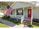 Inviting front porch with red door, American flag, rocking chairs, and well-maintained landscaping at 706 Chippendale Dr., Myrtle Beach, SC 29588